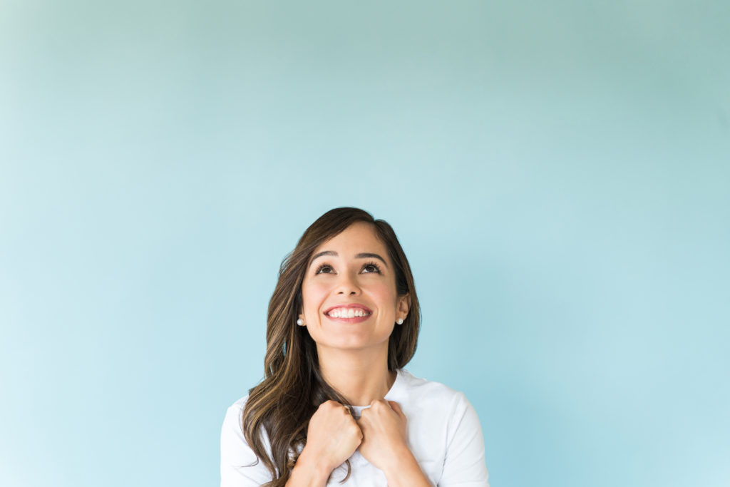 Excited thoughtful woman wishing while looking up over copy space on isolated background